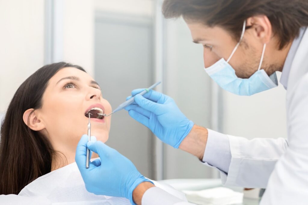 Tannlege undersøker pasientens tenner med speil og sonde under rutinekontroll.